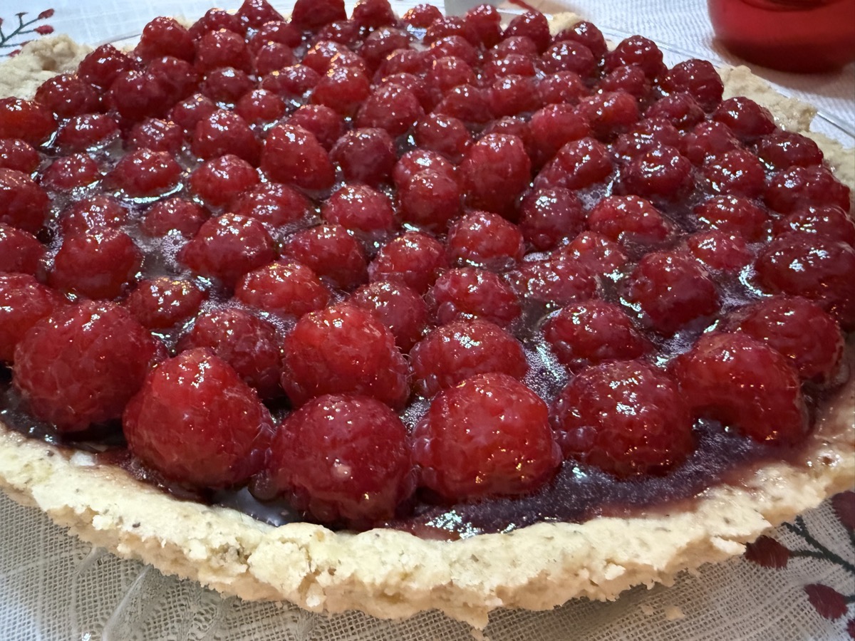 Fresh raspberry tart with glistening berries on a golden crust